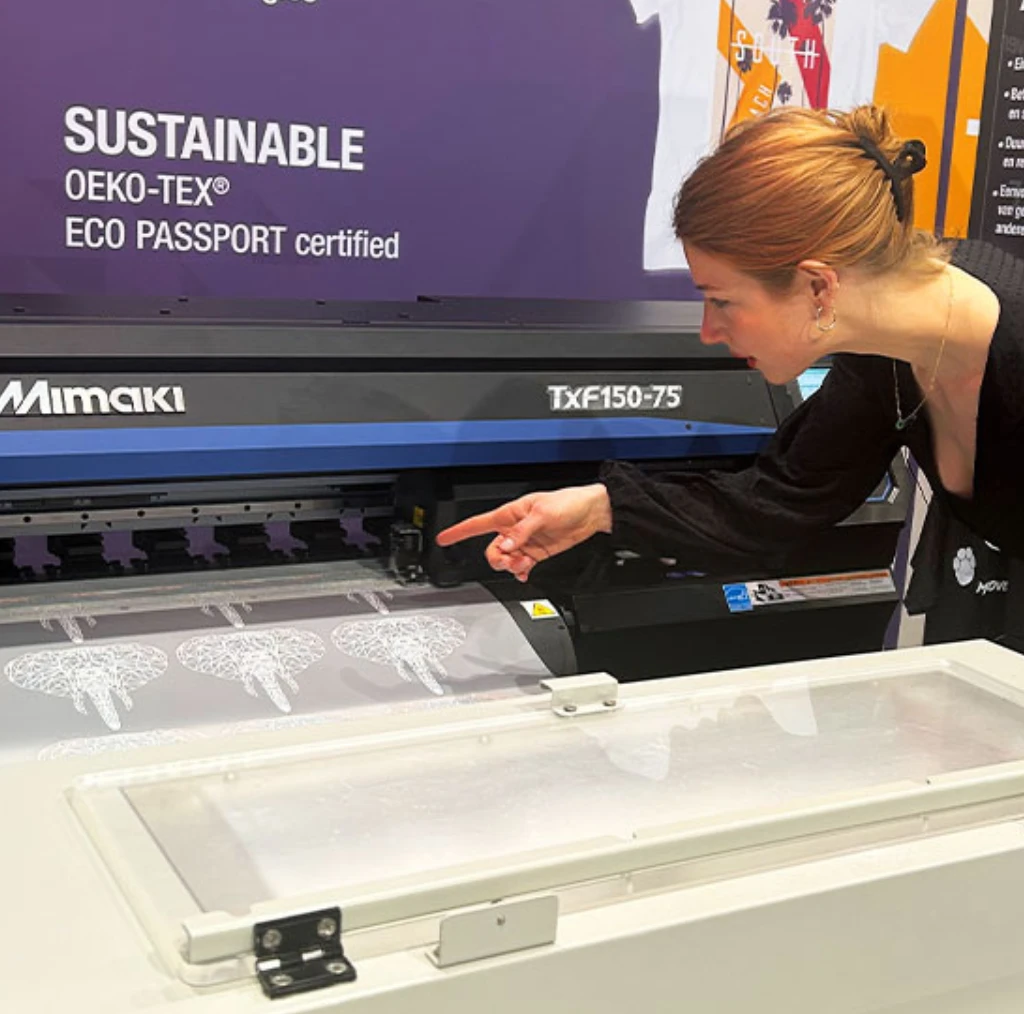 Operator using Mimaki TxF150-75 DTF printer demonstrating DTF printing technology