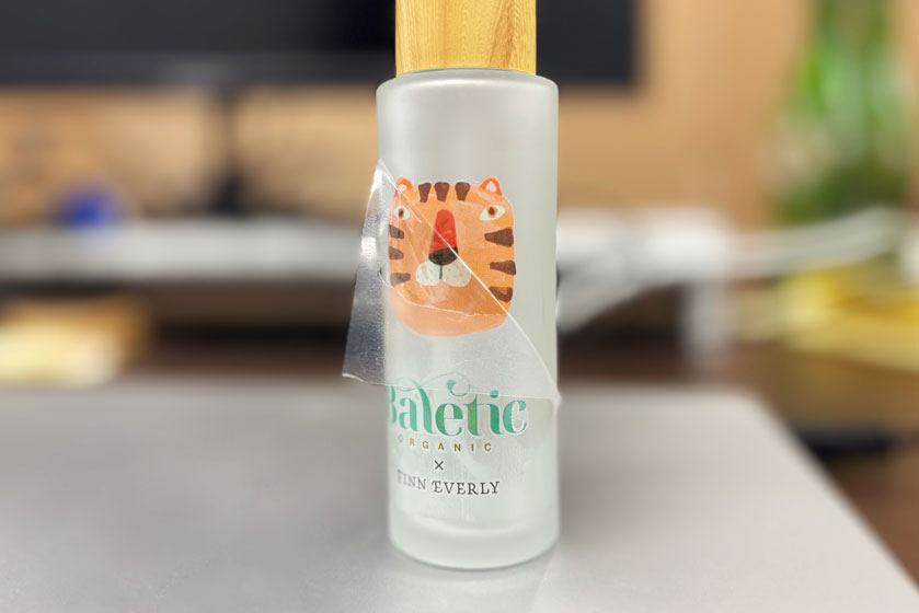 UV-DTF printed tiger design on frosted glass bottle — Baletic Organic x Finn Everly custom label application